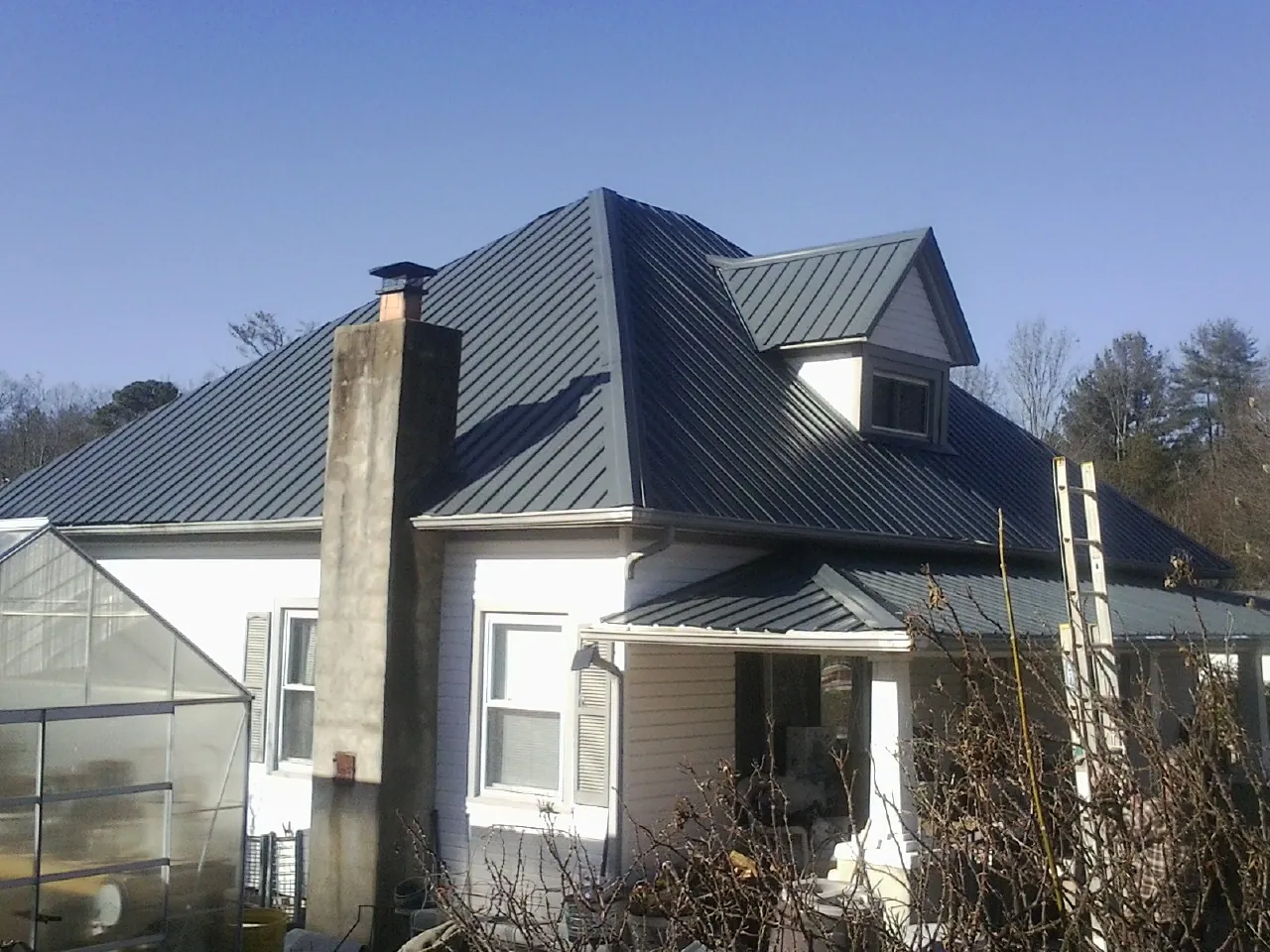 Dark blue standing seam metal roof on a white farmhouse with dormer — Slate & Tile Roof Repair by Roofing Brothers in Ickesburg