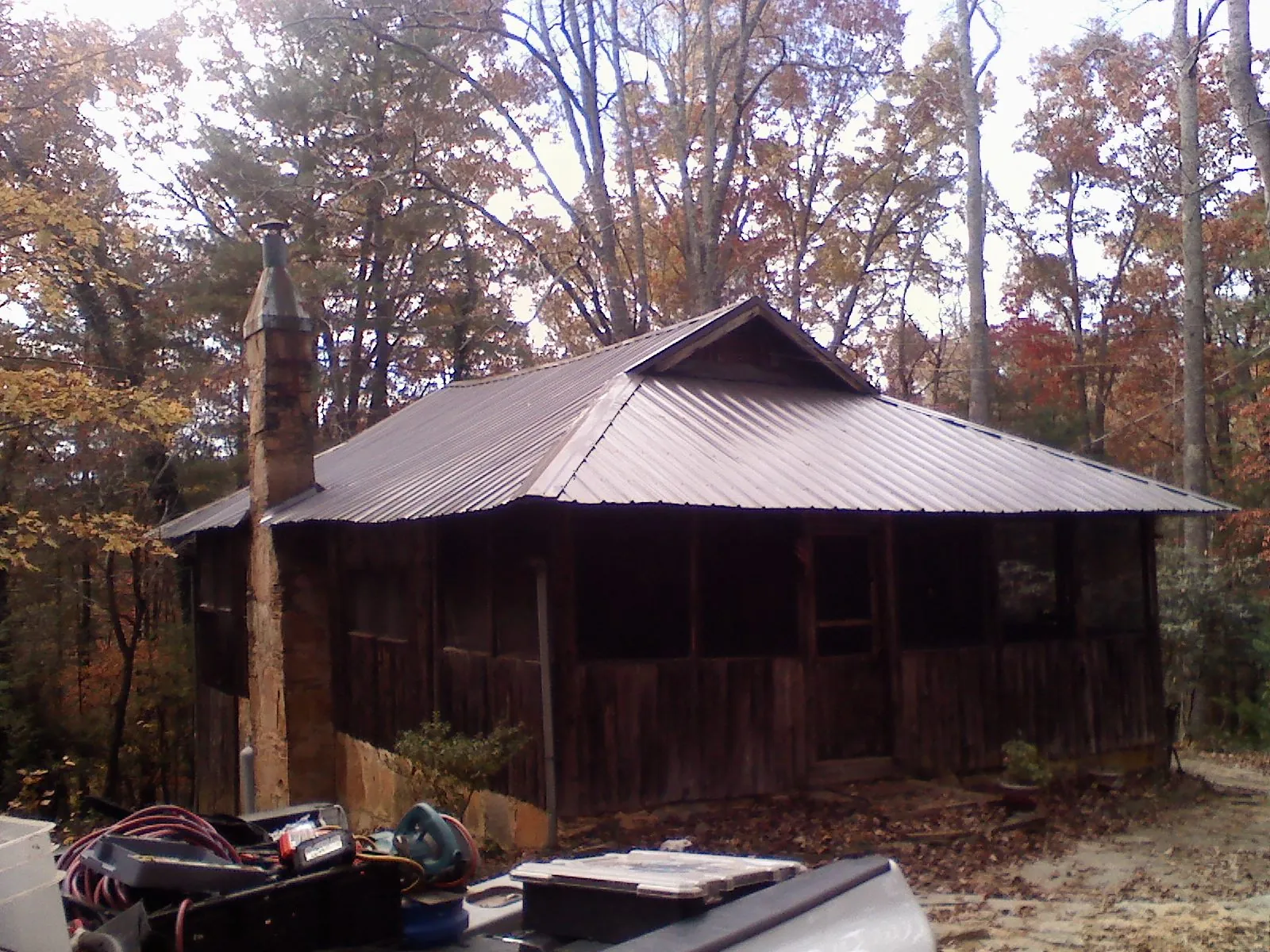 Brown metal hip roof on an old cabin with a stone chimney in Ickesburg