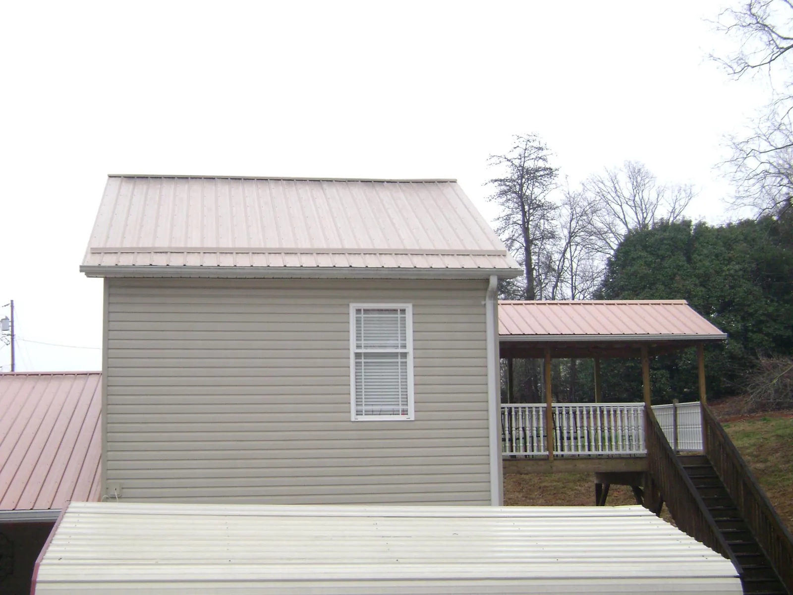 Tan metal roofs on a two story addition and attached porch, from a Roof Replacement job in Ickesburg