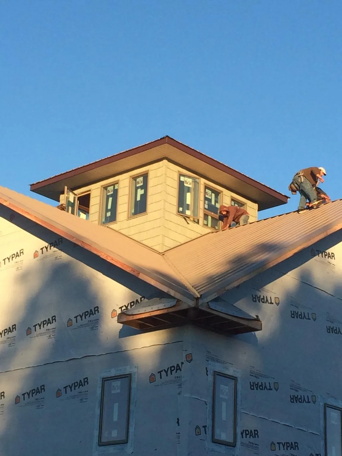 Roofers working around a rooftop cupola on a new metal roof at sunset — Roof Waterproofing in Ickesburg by Roofing Brothers
